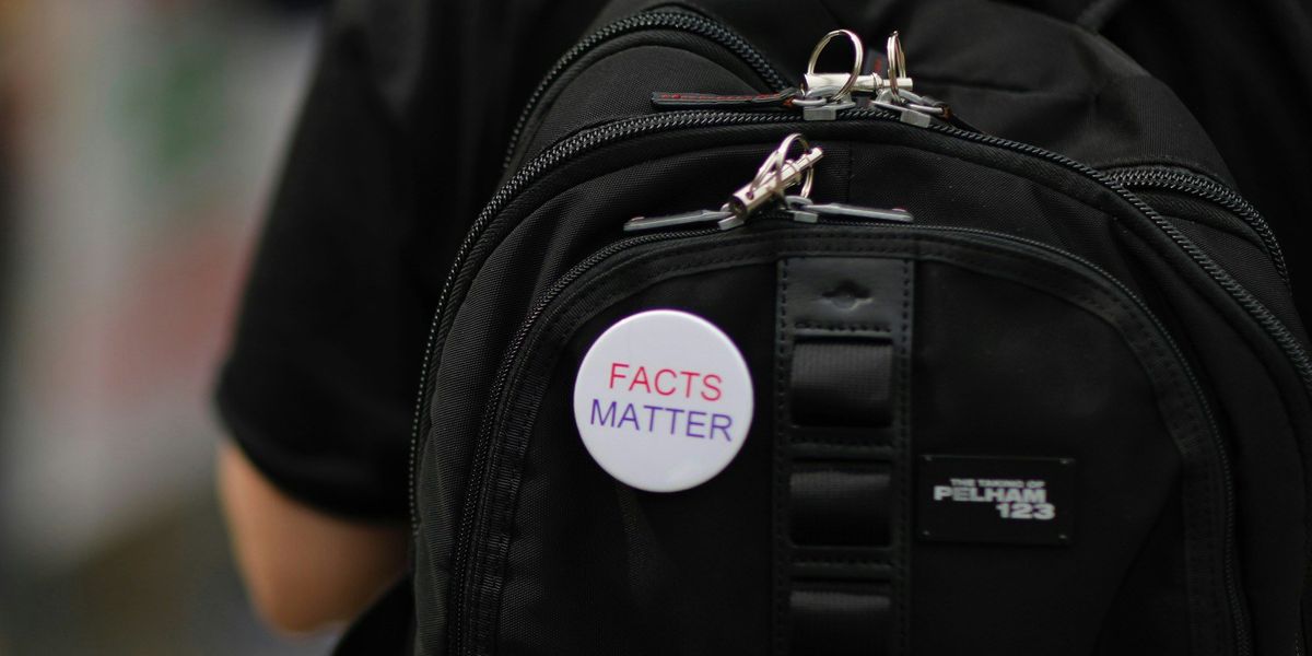 FACTS MATTER pin on a black backpack on a person's back