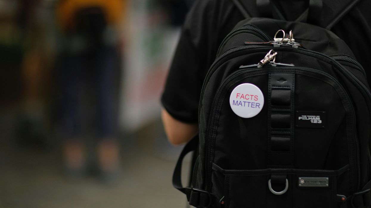 FACTS MATTER pin on a black backpack on a person's back