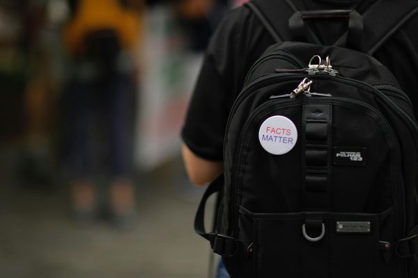 FACTS MATTER pin on a black backpack on a person's back