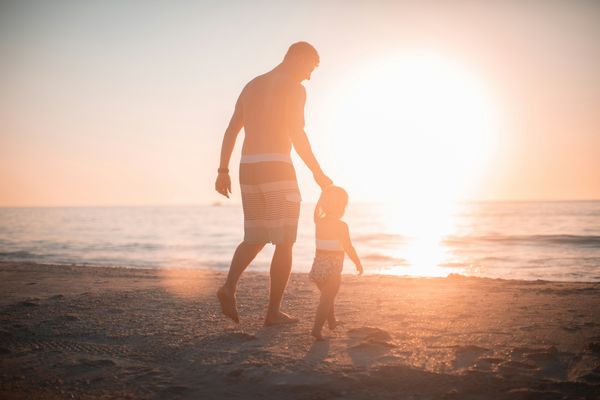 Father and kid at a beach at sunset