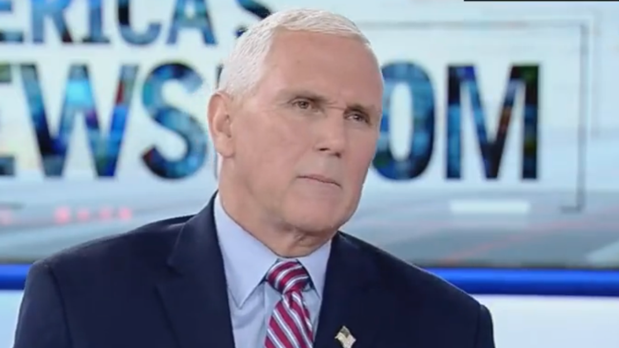 former Vice President Mike Pence, wearing a dark blue suit jacket, a light blue shirt, and a red, white, and blue striped tie