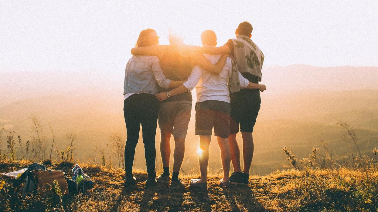 Four friends hold onto one another looking off into the horizon