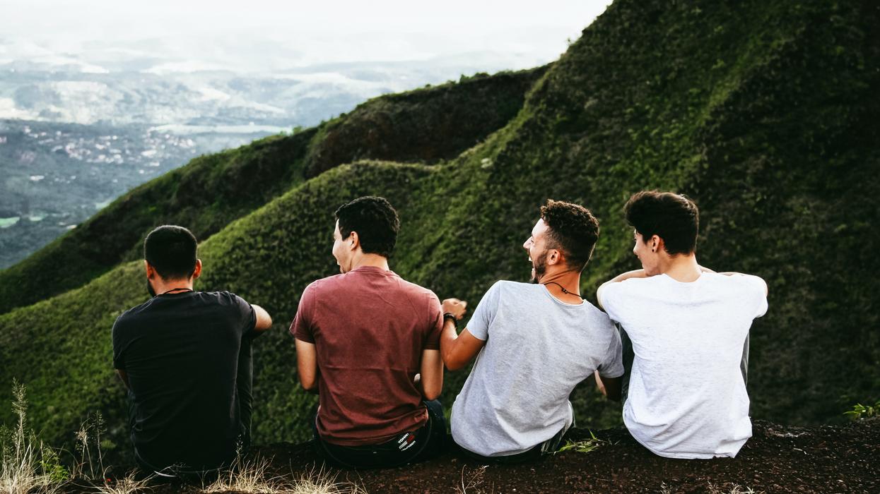 Four men sitting on a hill and laughing