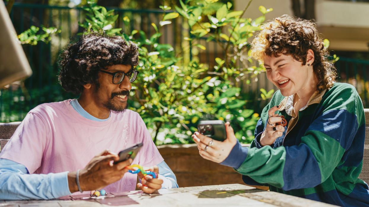 friends sitting outside using stim toys and laughing at their phones