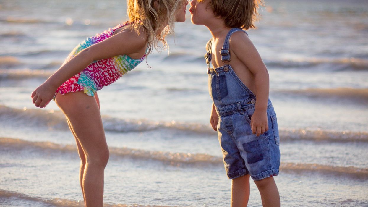 girl and boy kissing on beach during daytime