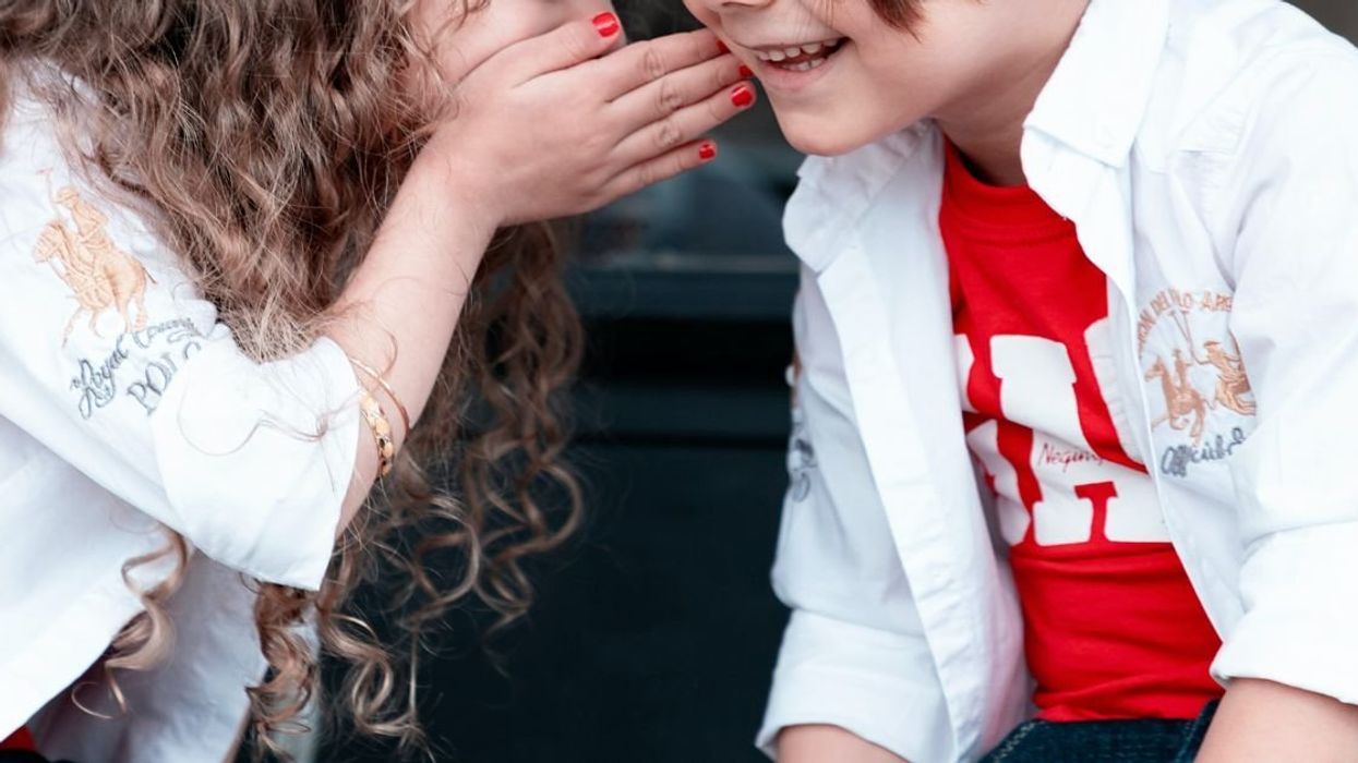 Girl whispering into a boy's ear