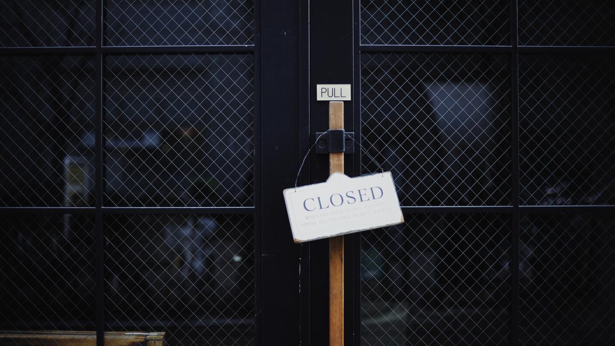 Glass doors with a Closed sign hanging in front.