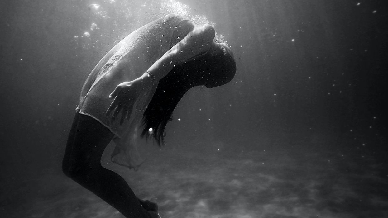 grayscale photo of woman drowning in water