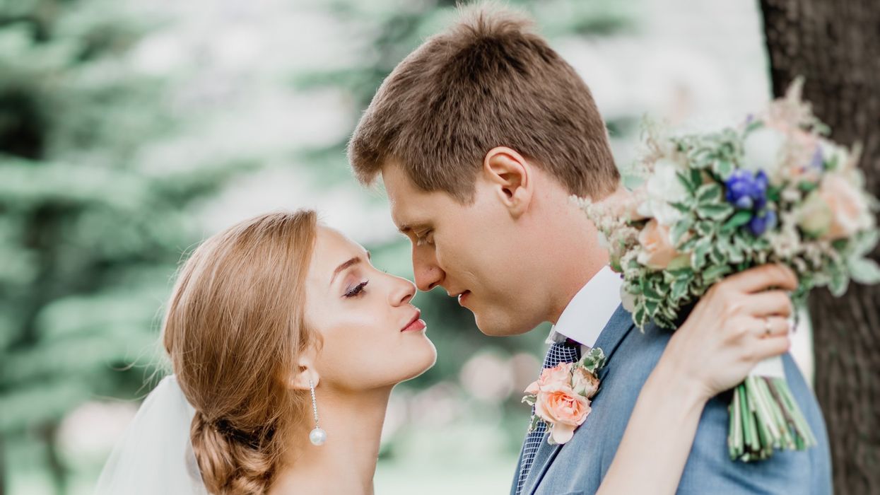 groom in gray suit kissing bride in white dress