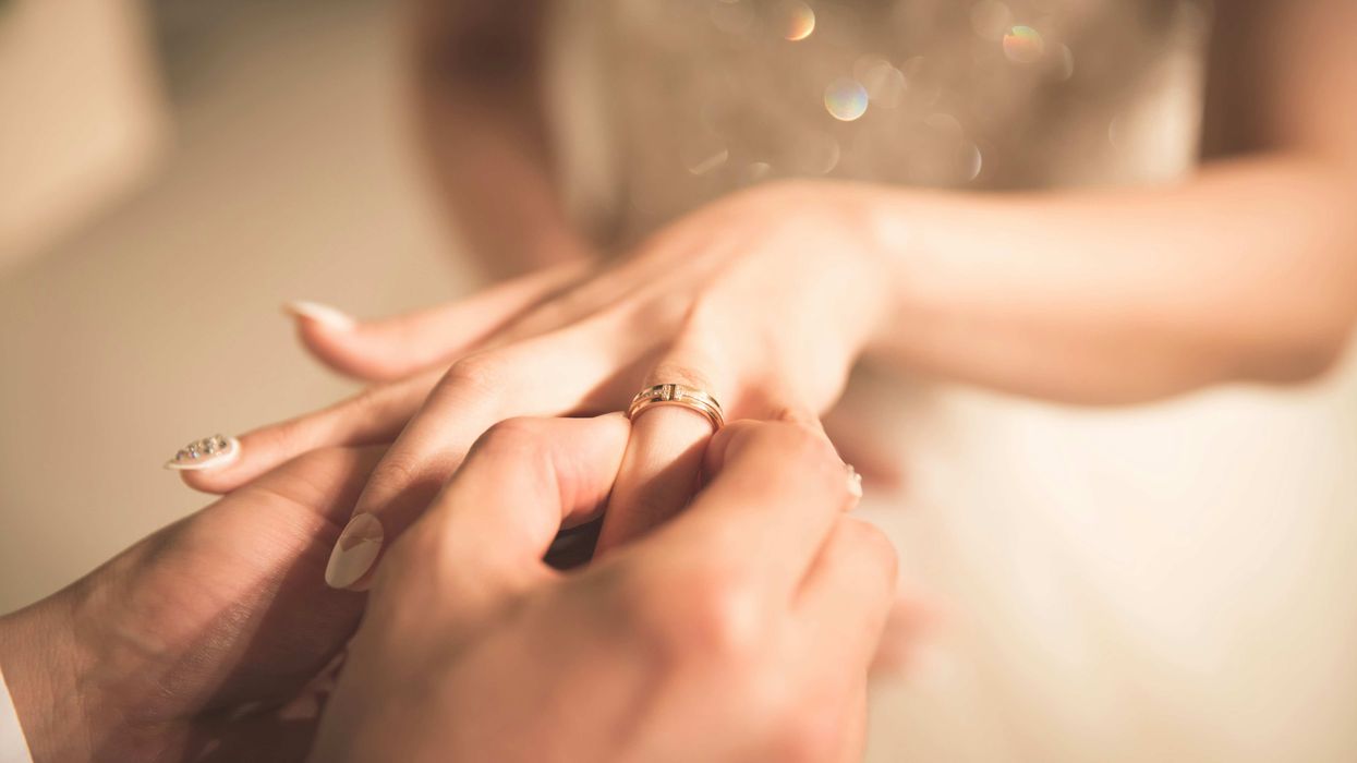 Groom placing wedding ring on bride's finger