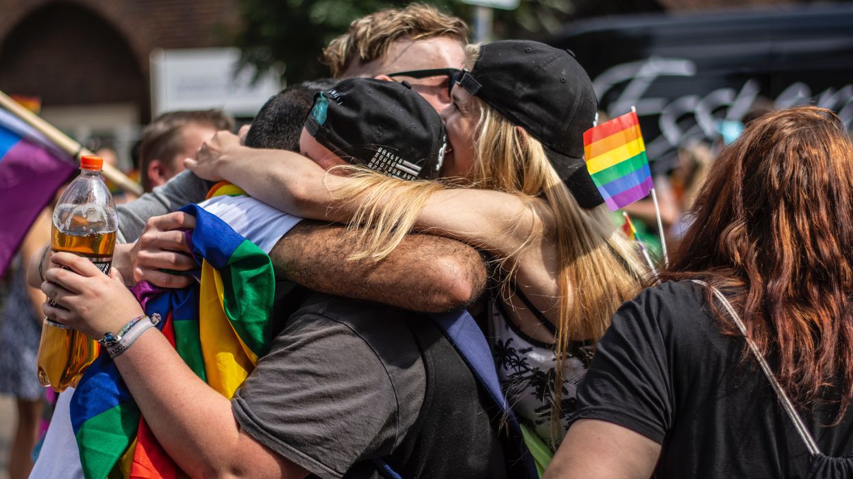 Group hug with people holding rainbow flags