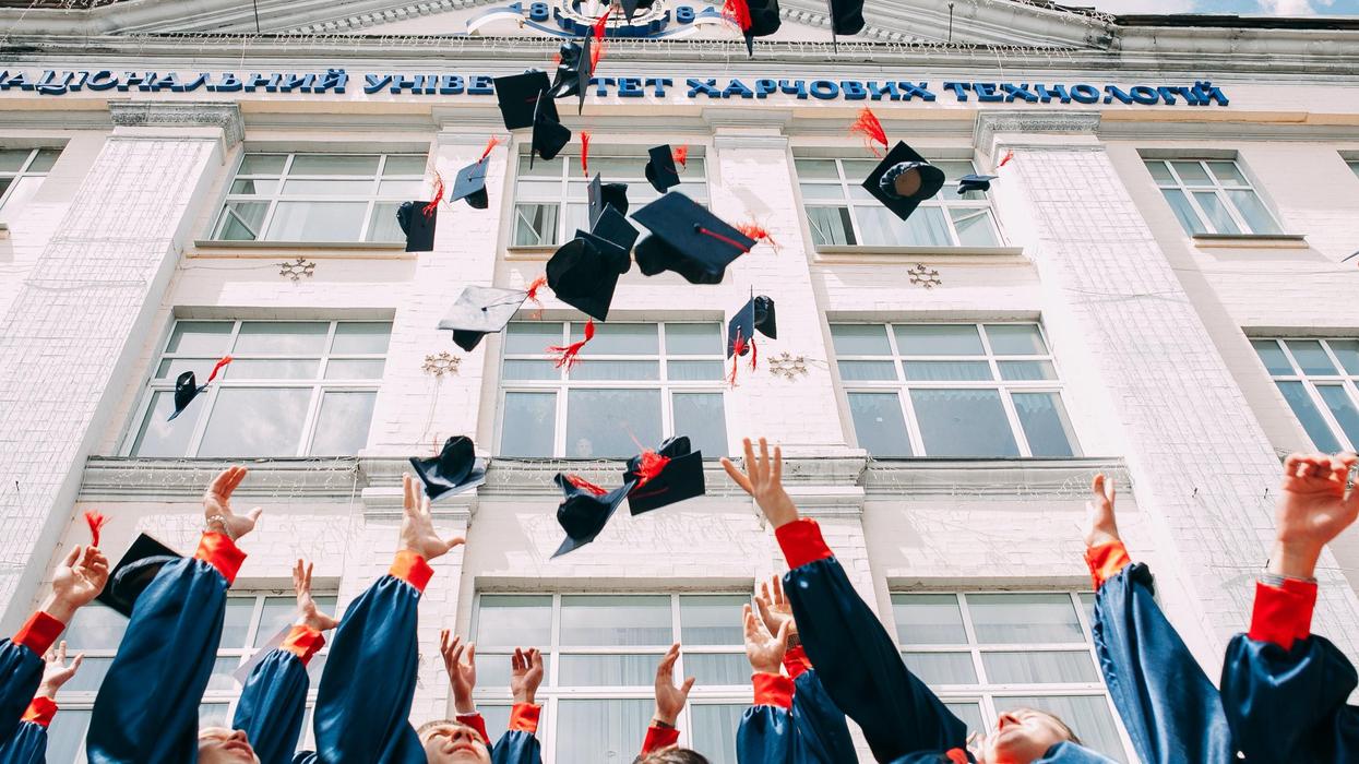 group of fresh graduates students throwing their academic hat in the air