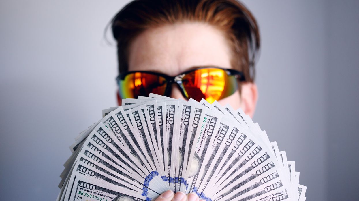 Guy holding up a fan of $100 US dollars