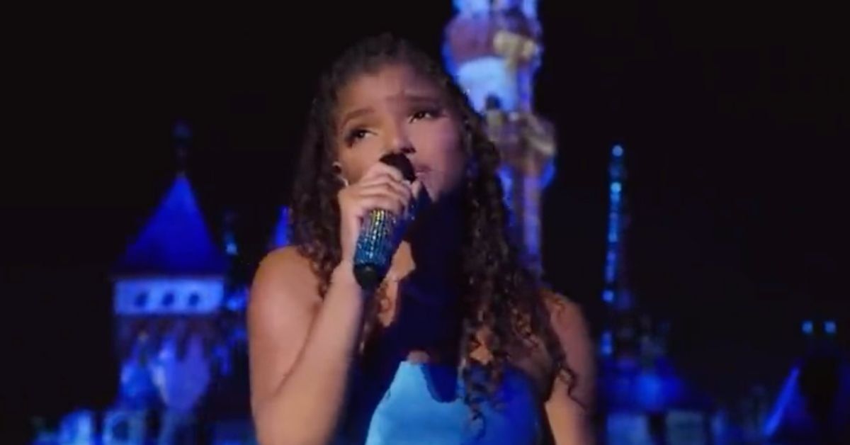 Halle Bailey singing in front of Disneyland castle