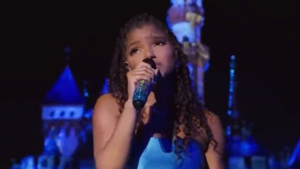 Halle Bailey singing in front of Disneyland castle