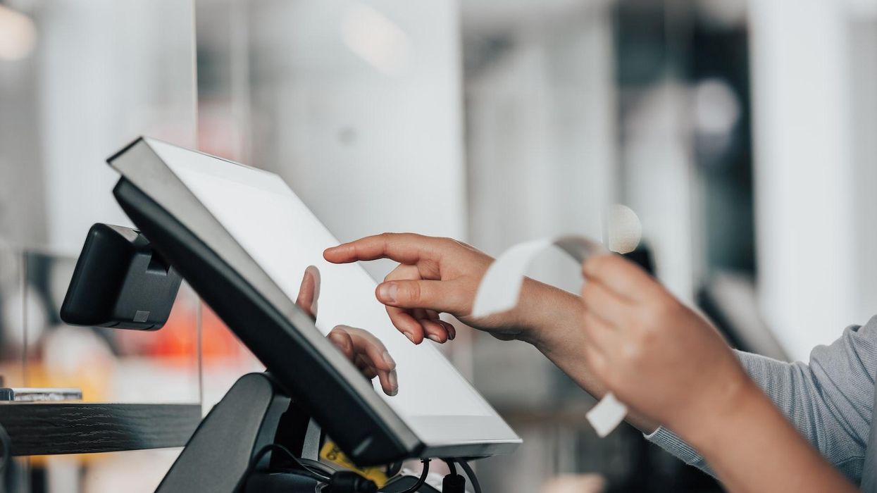 Hand holding a receipt and using a tablet