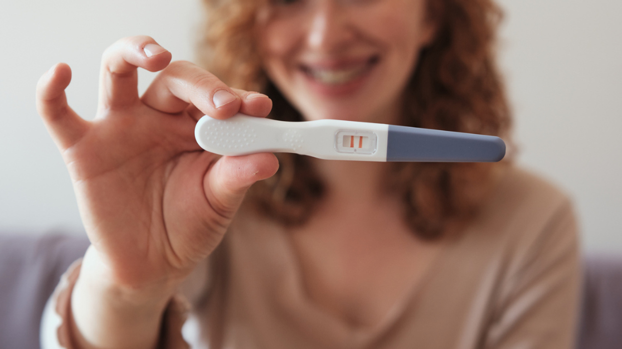 Happy woman holding up a positive pregnancy test