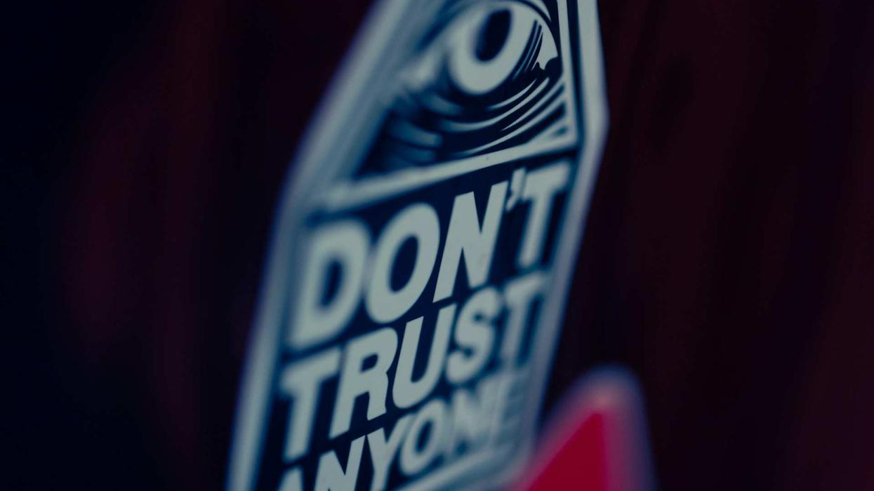 Image of close-up, blurry shot of a sign that says... "Don't Trust Anyone."