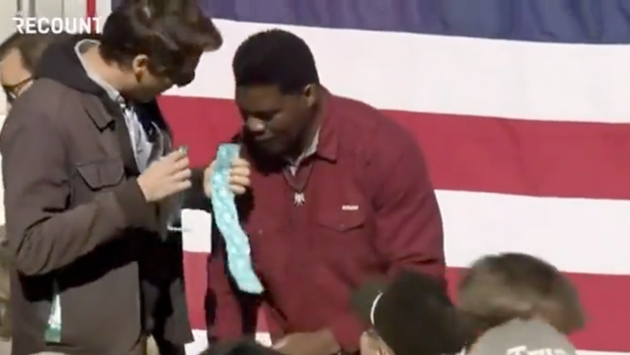 Prankster Comedian Interrupts Herschel Walker Campaign Event To Hand Him Condoms In Viral Video