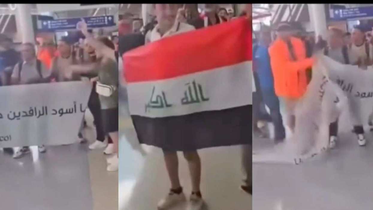 Iraqi soccer fans hold a banner at Dallas Fort Worth International Airport as a man in an orange jacket confronts them and tears it down.