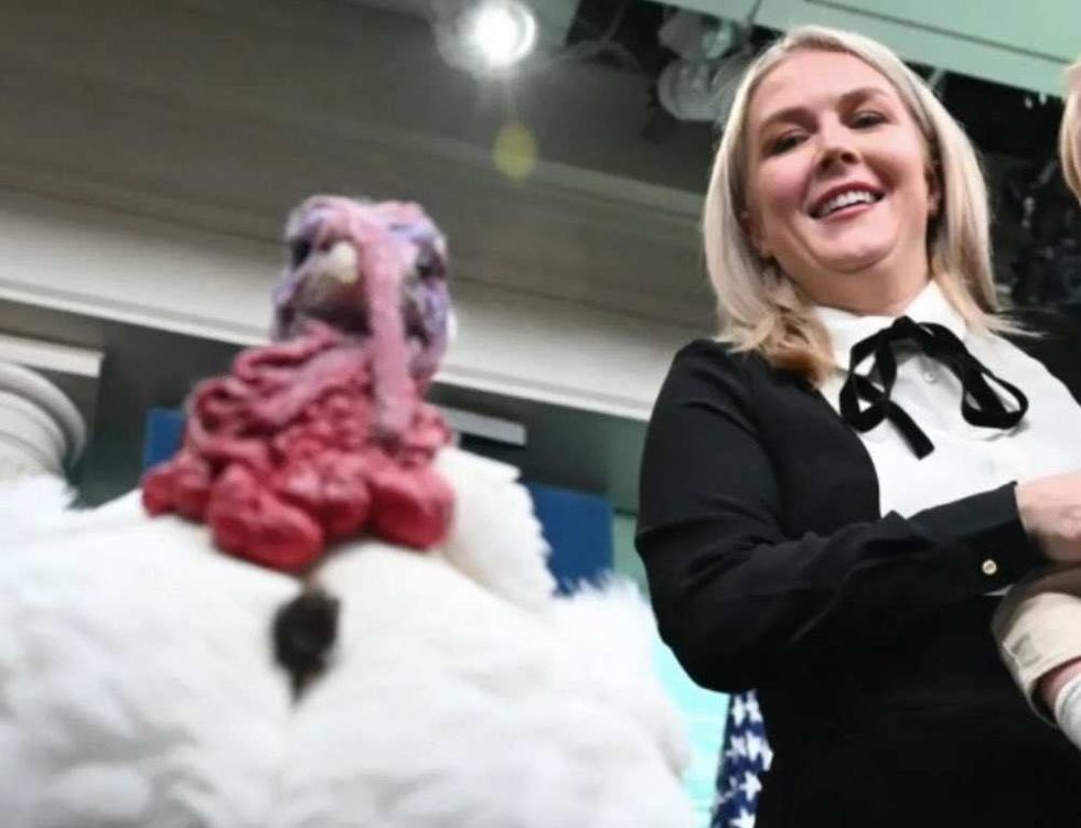 Karoline Leavitt holding her son while standing next to a turkey