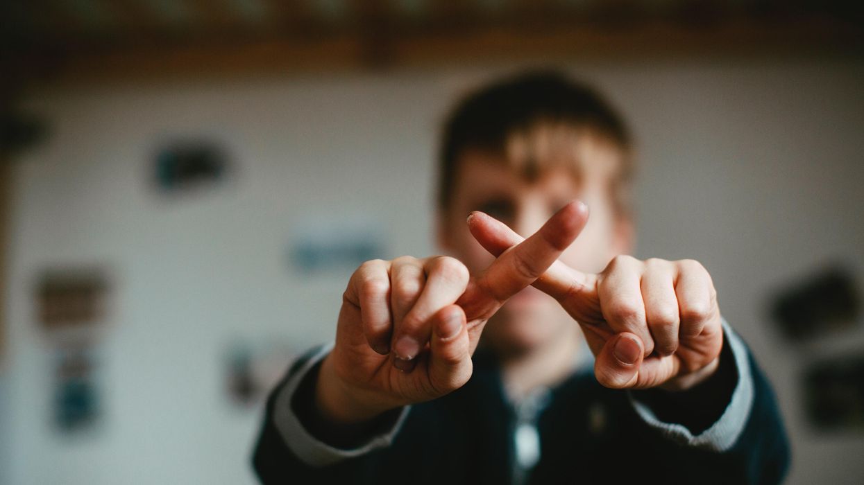 Kid forming a cross with two fingers