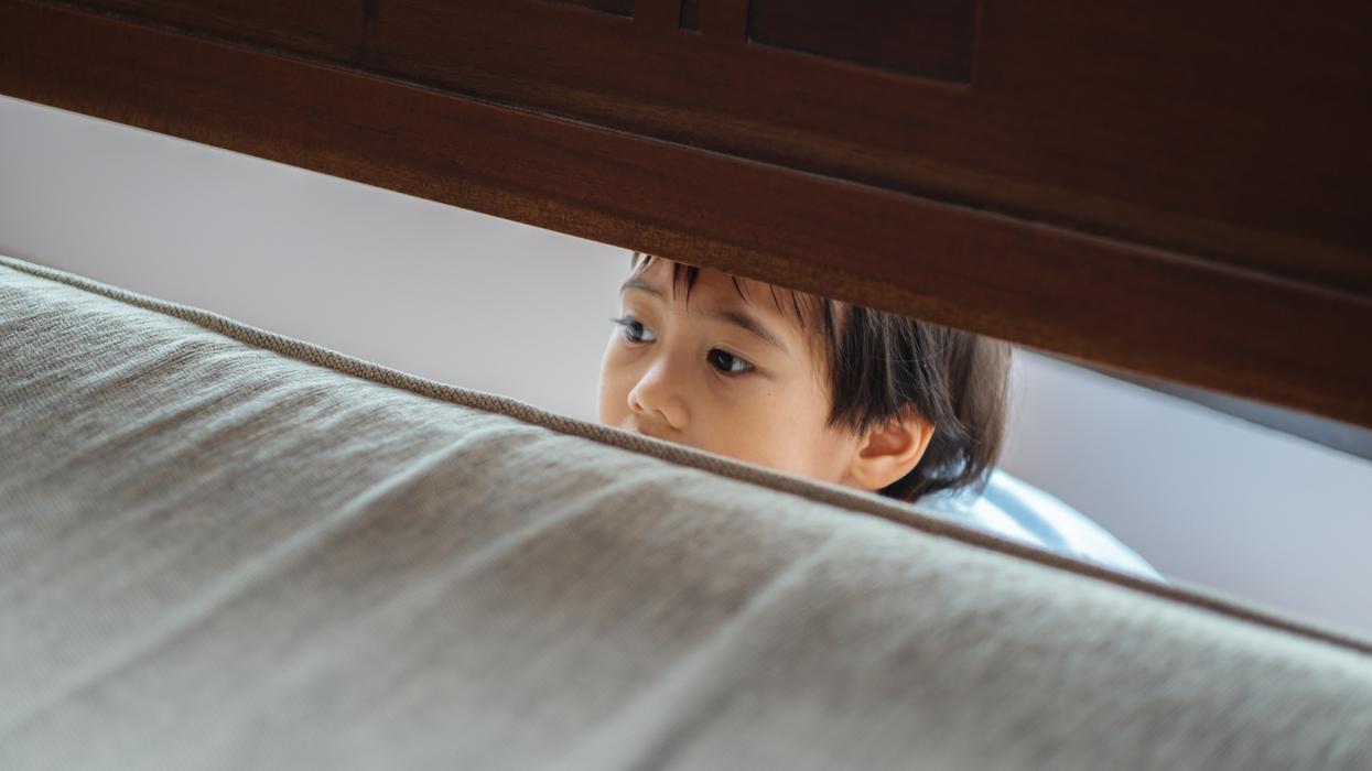 Little boy peeking through a crack