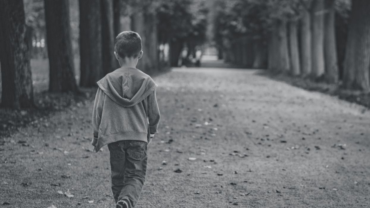 Little boy walking alone down the road