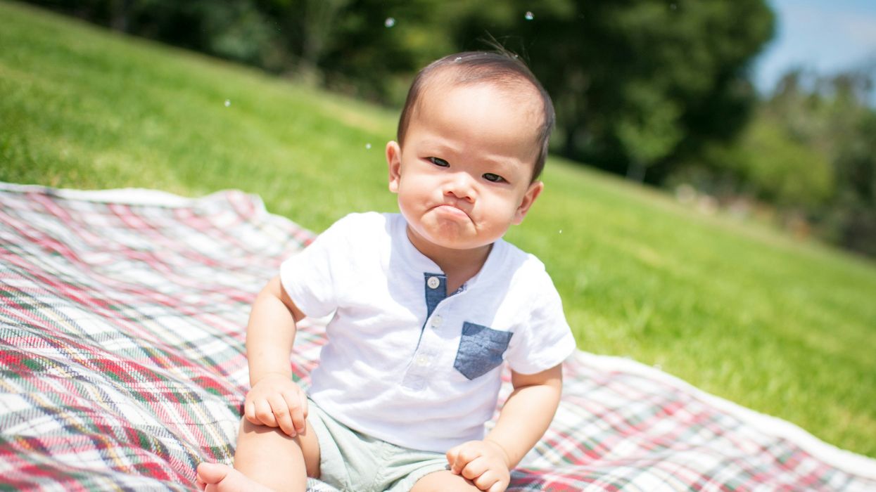 mad baby sitting on plaid blanket