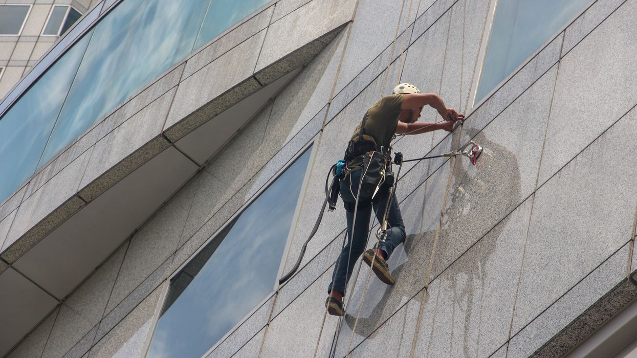 Maintenance worker dangling on the side of a skyscraper
