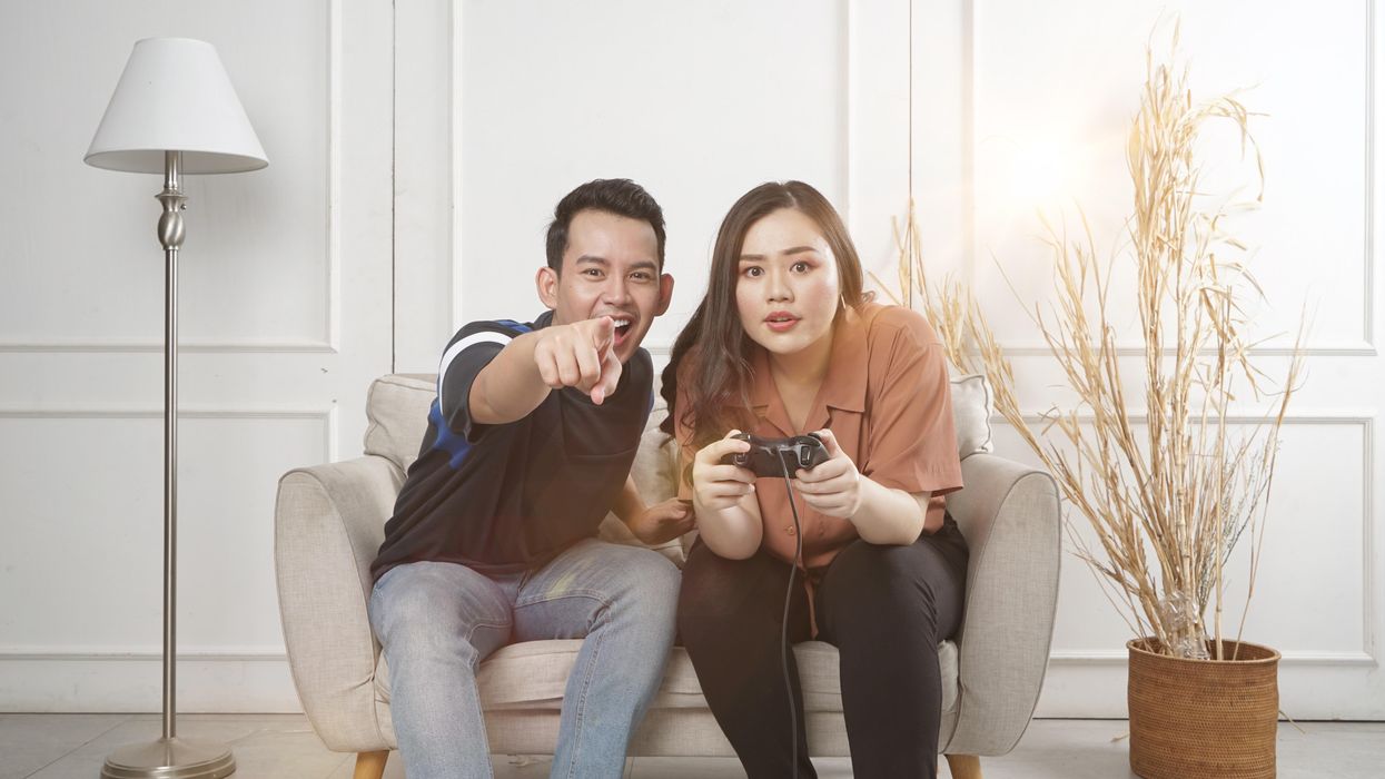 man and woman siting on loveseat playing video game