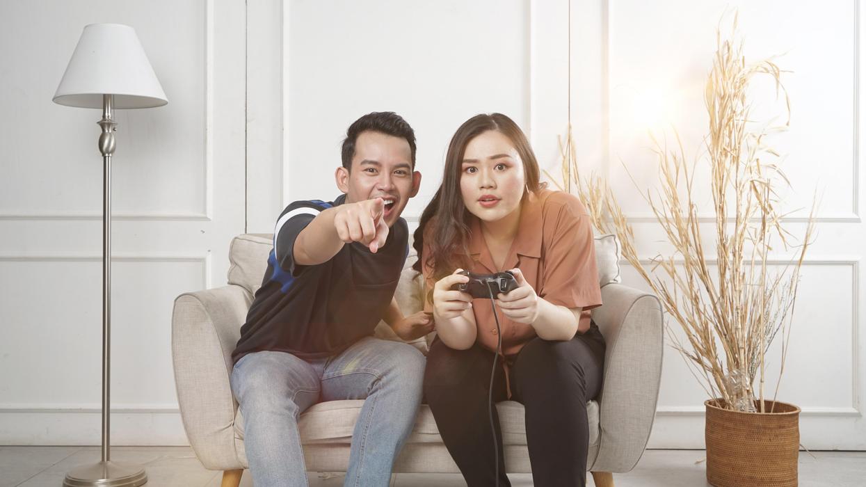 man and woman siting on loveseat playing video game