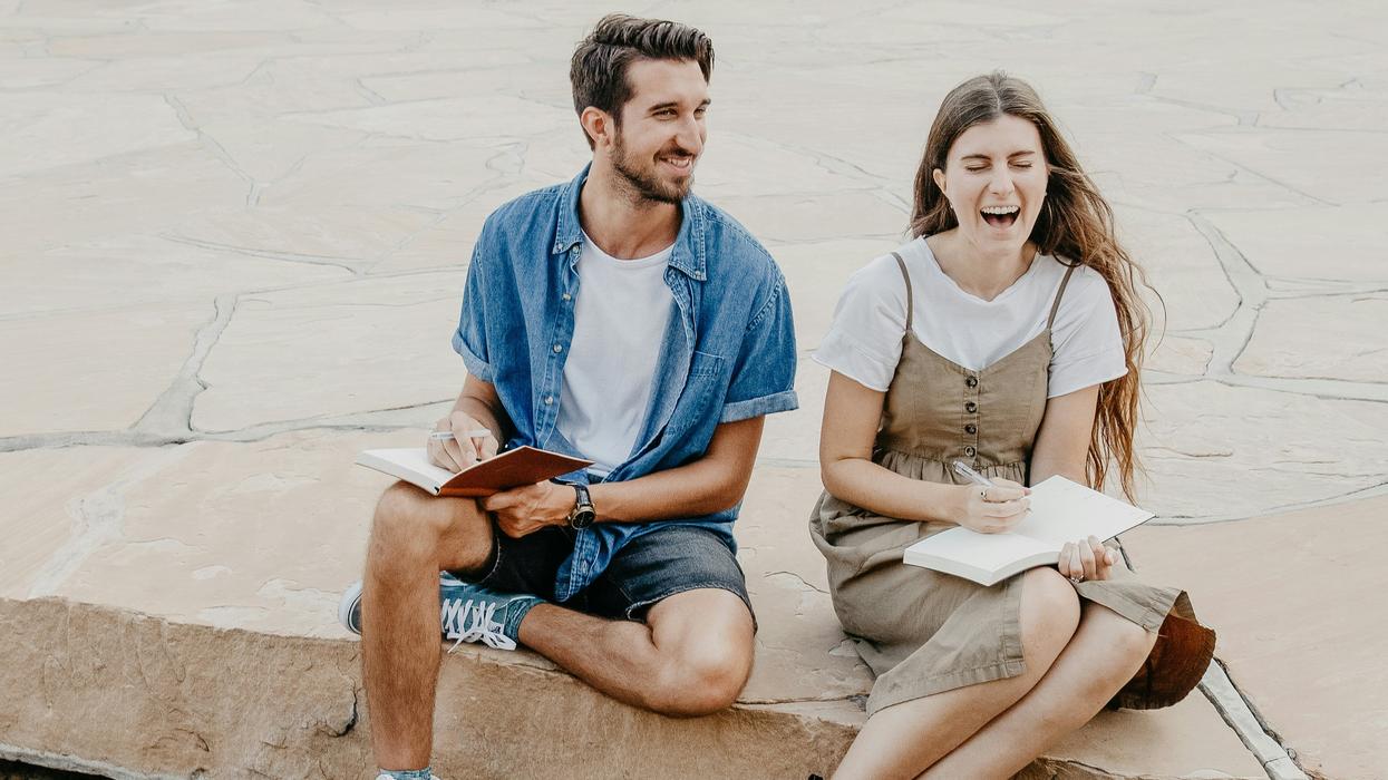 man and woman sitting side by side holding notebooks