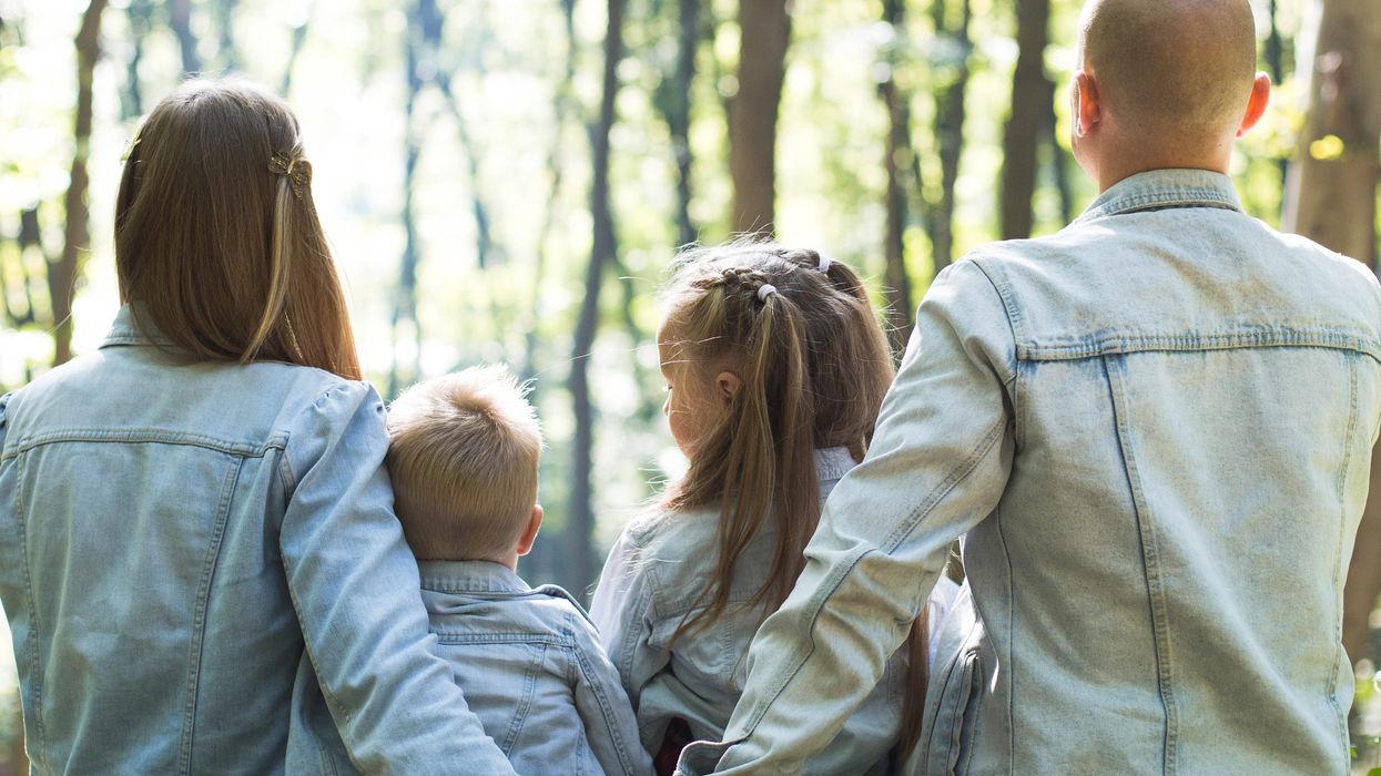 man and woman together with boy and girl looking at green trees during day