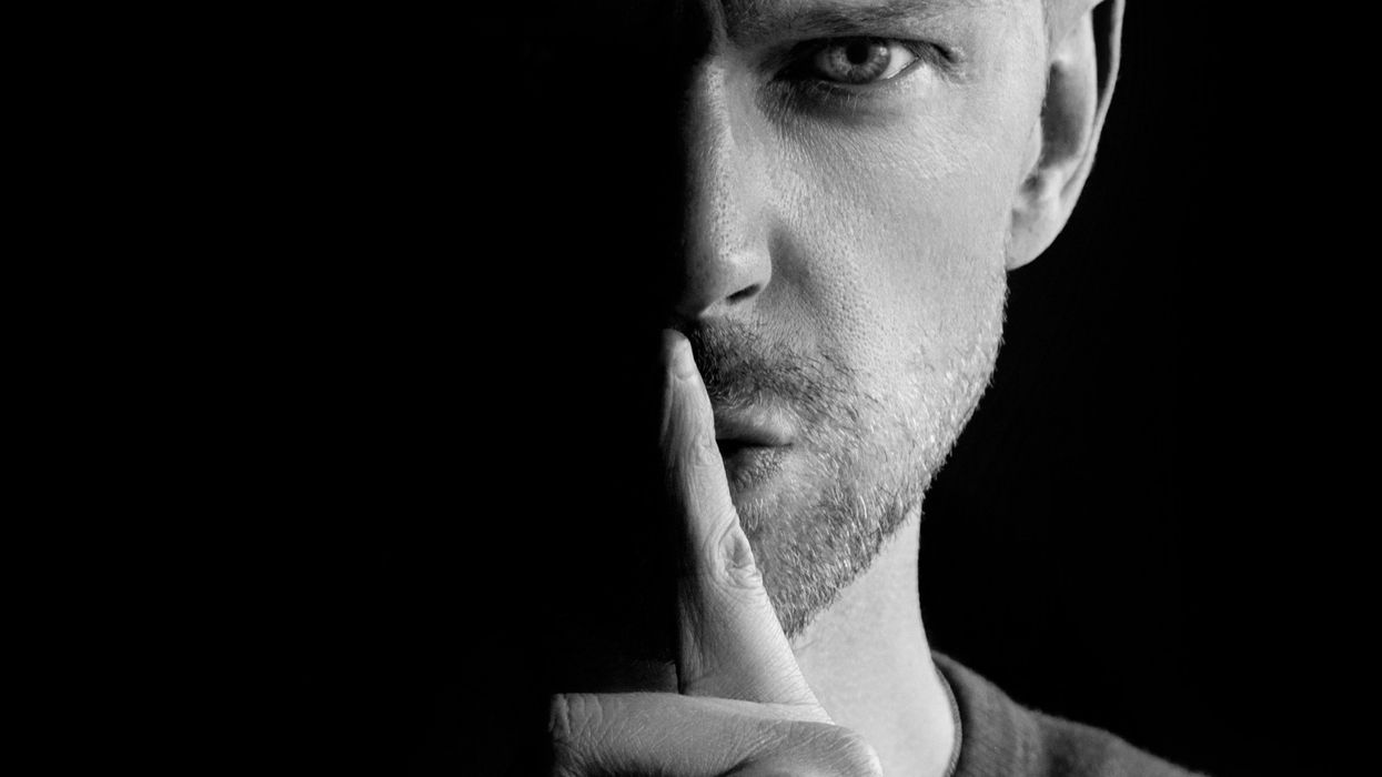 Man holding a finger against his lips in a 'Shh!' gesture