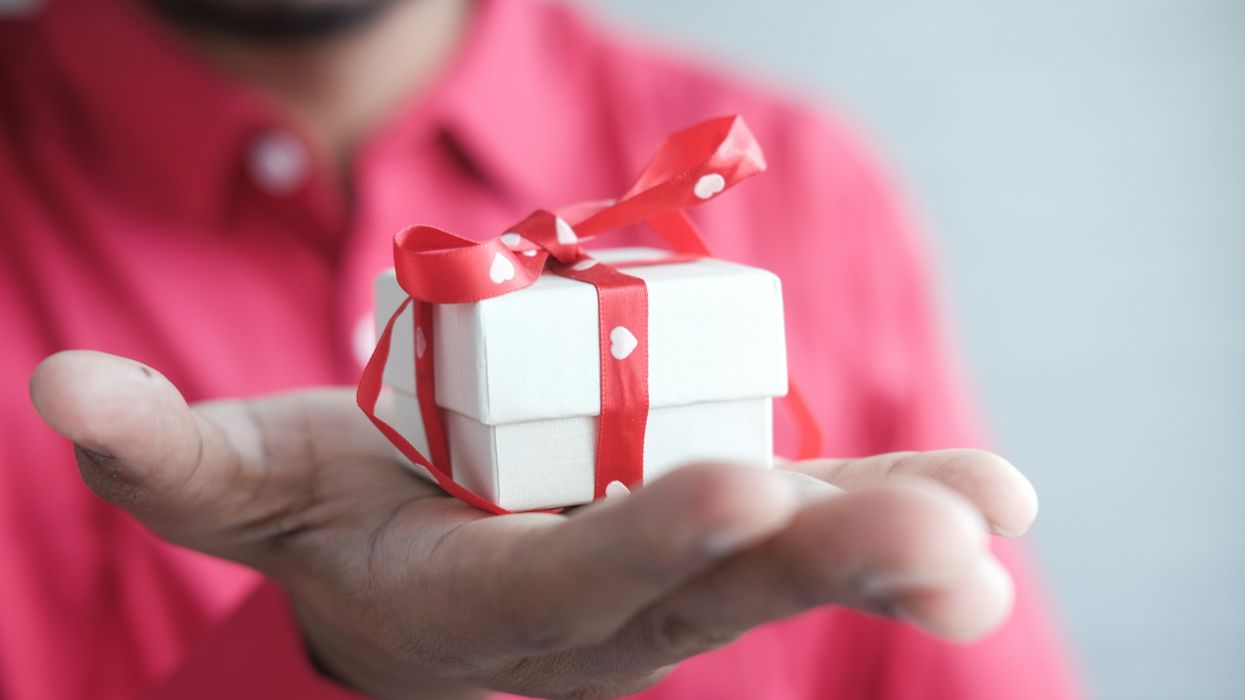 Man holding a white box wrapped in a red ribbon