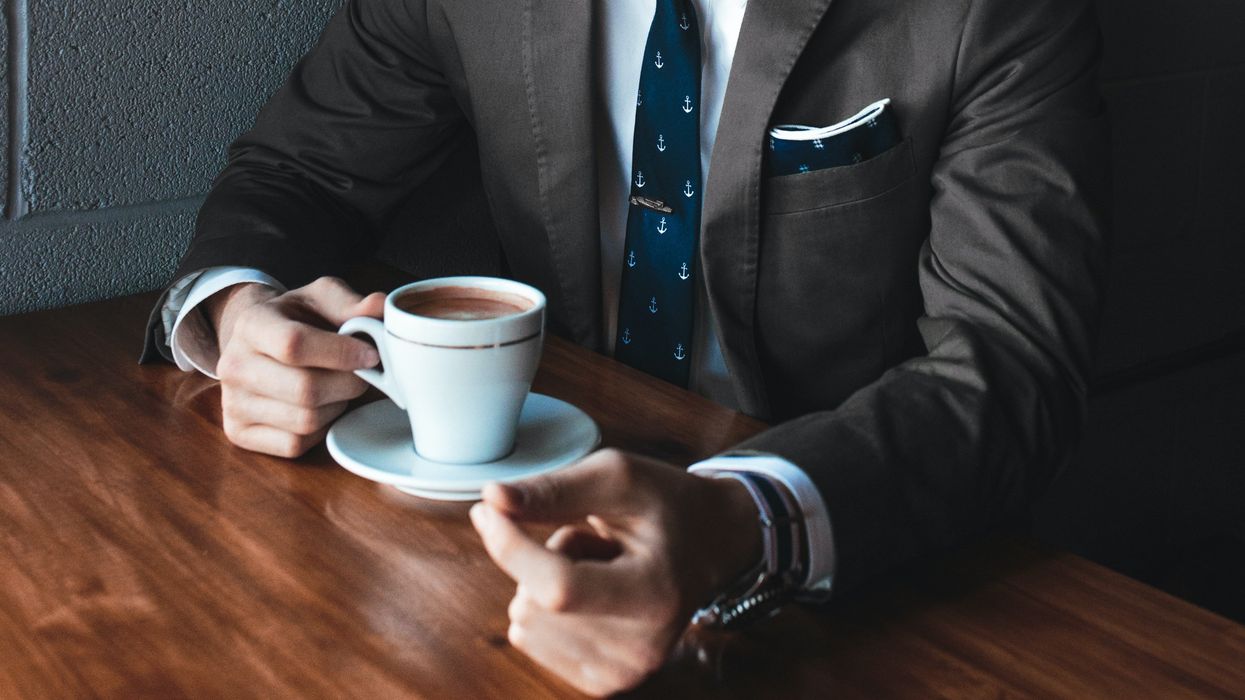 man holding cup filled with coffee on table