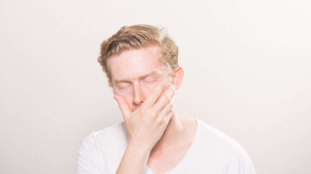 Man holding his hand over his mouth with his eyes shut