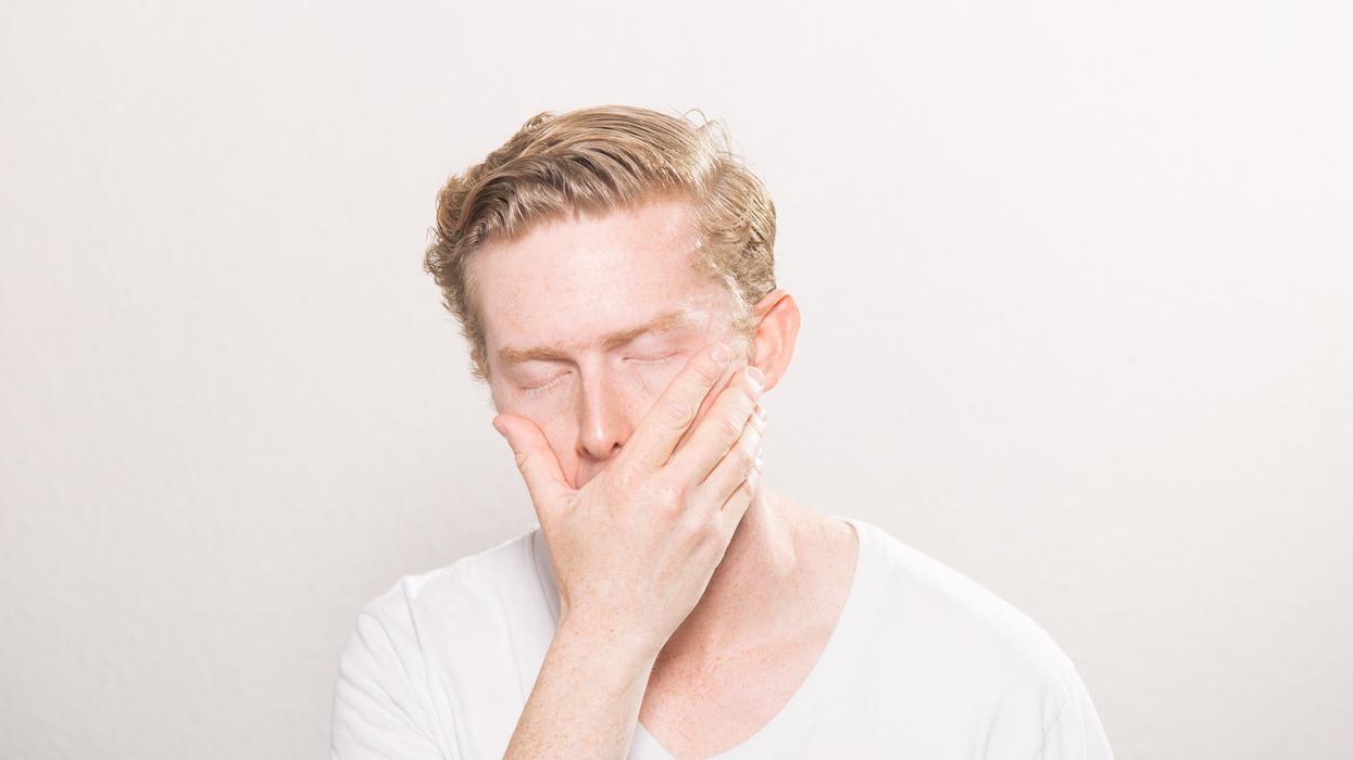 Man holding his hand over his mouth with his eyes shut