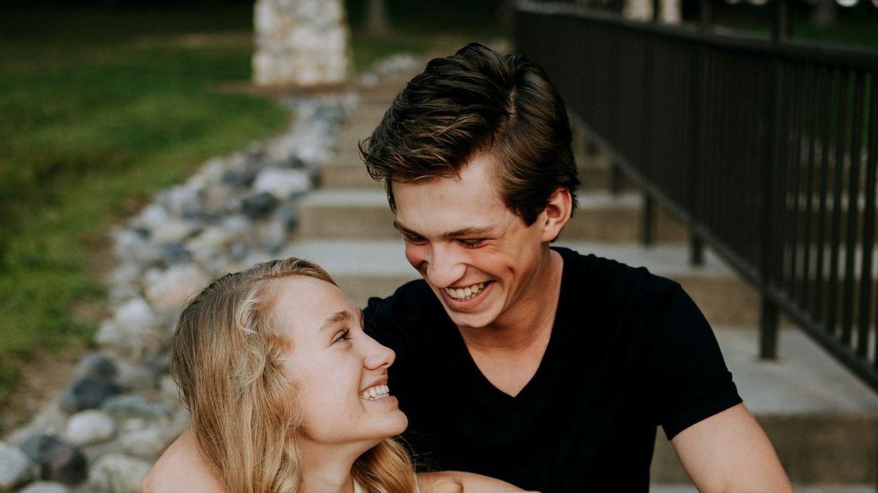 man holding the hand of a woman while siting on concrete staircase
