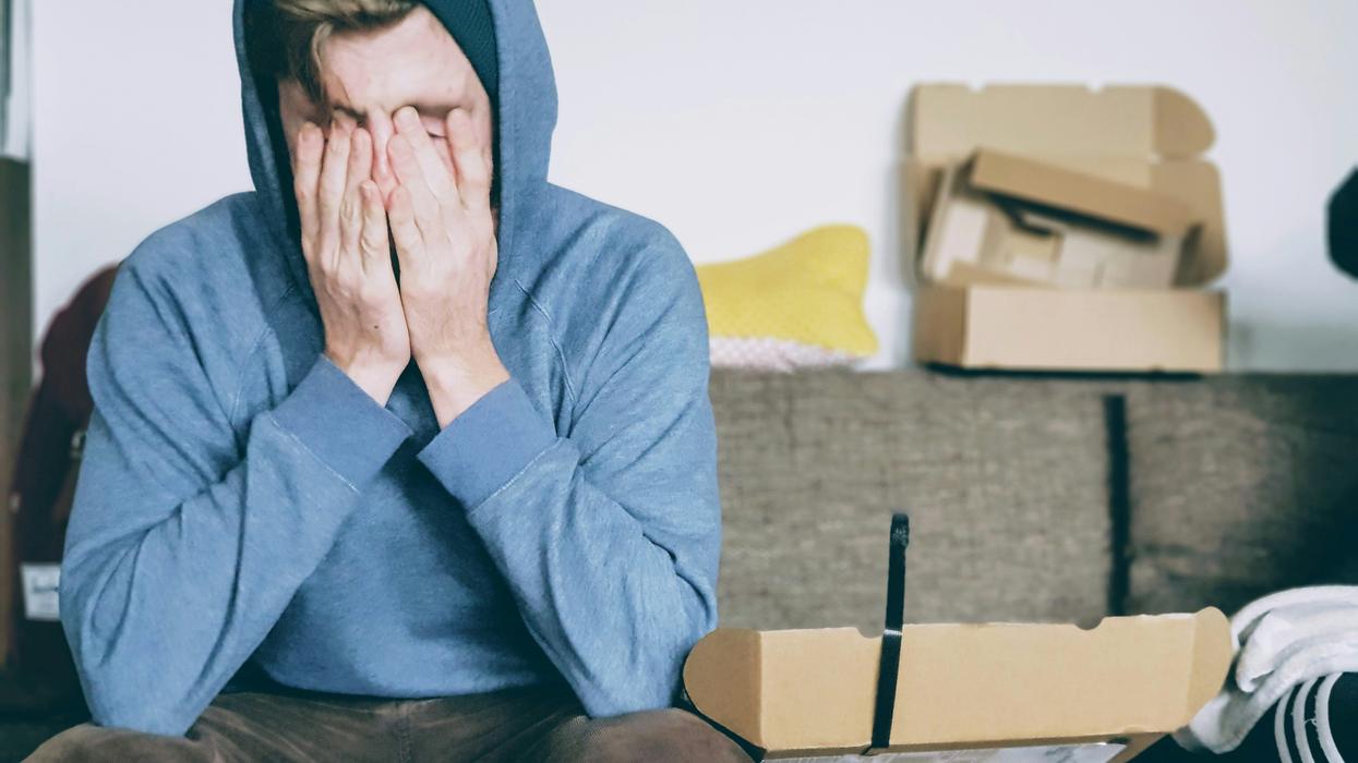 Man in a hoodie with his face in his hands