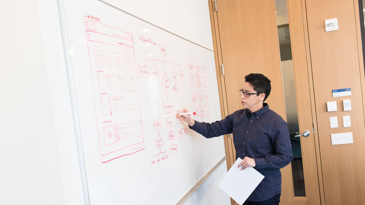 man in black dress shirt writing on dry-erase board