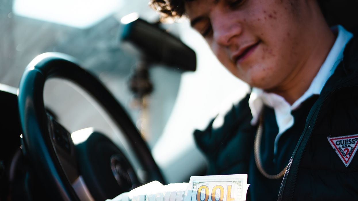 man in car holding a lot of American money