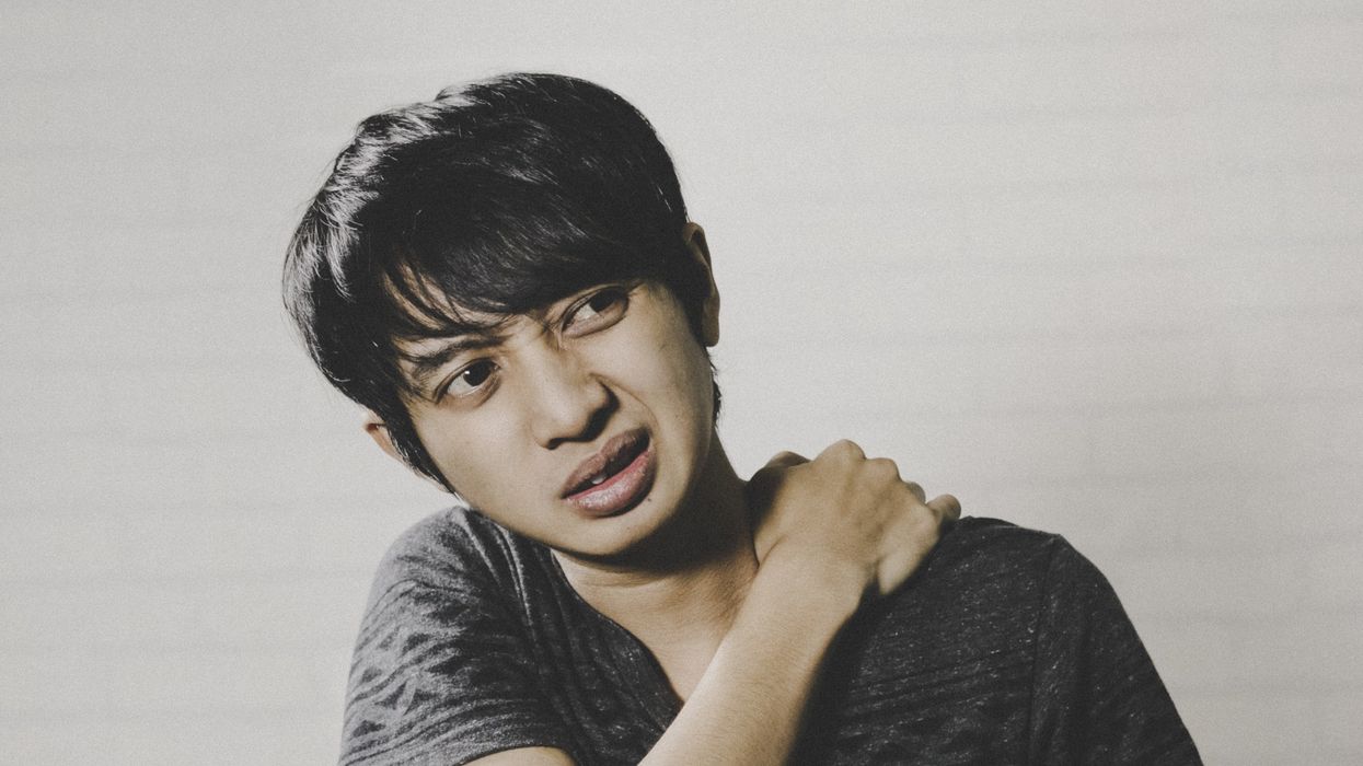 Man in pain, massaging neck and shoulder