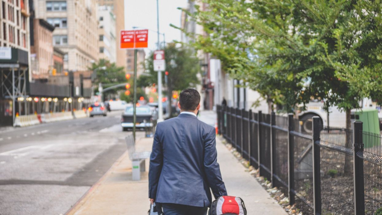 Man in suit walking down the street with two bags