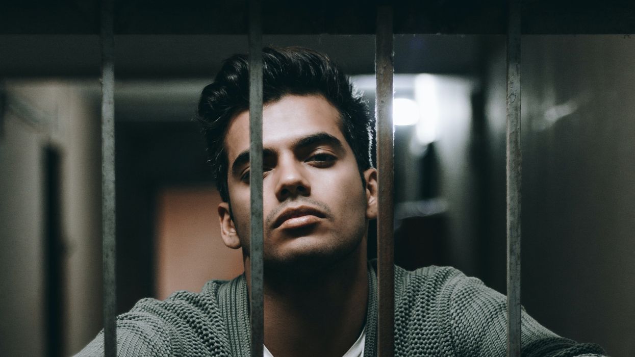 Man leaning forward into prison bars