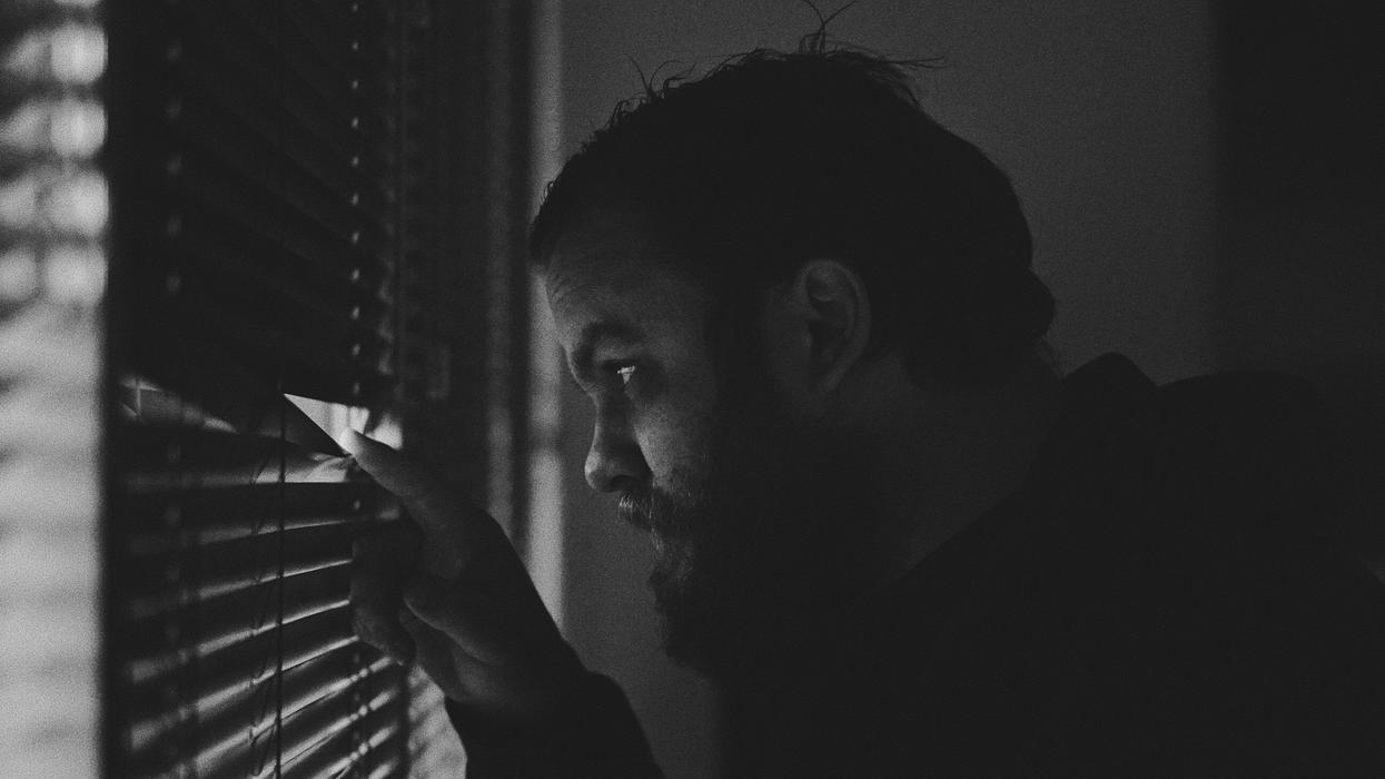 Man peeking through window blinds