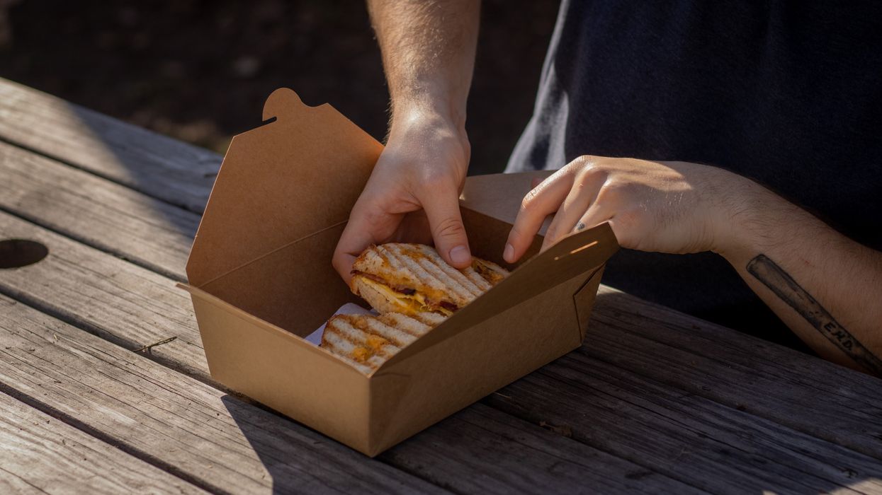 Man putting a sandwich in a to go box