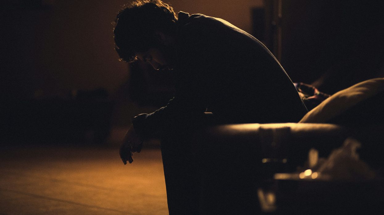 Man sitting in silhouette with his head down