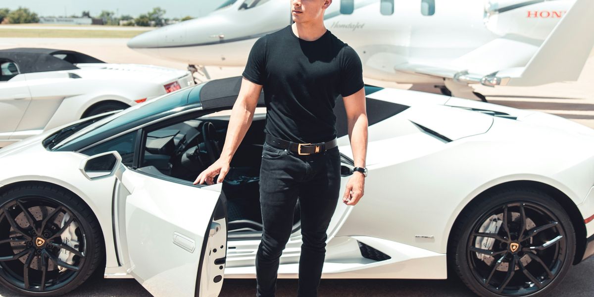 man standing in front of expensive cars and private jet